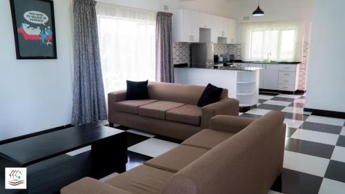 a living room with a couch and a table and a kitchen at Likulezi Apartment 1 in Blantyre