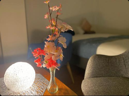 a vase with flowers on a table in a bedroom at THE MOON Atami in Atami