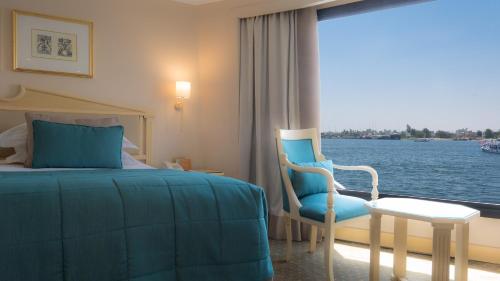 a hotel room with a bed and a chair and a window at Steigenberger Royale Nile Cruise - Every Thursday from Luxor for 07 & 04 Nights - Every Monday From Aswan for 03 Nights in Aswan