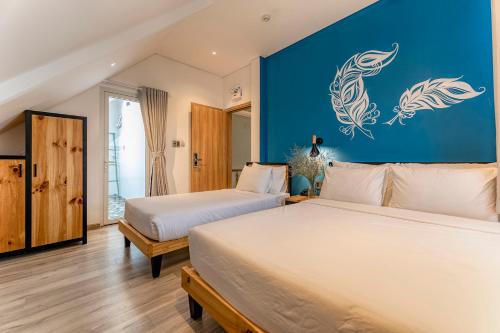 two beds in a bedroom with a blue wall at Canary Dalat Hotel in Da Lat