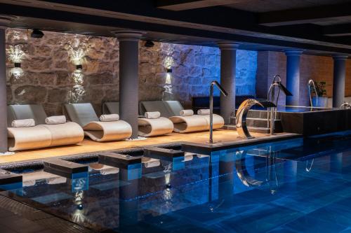 einen Pool in einem Hotel mit Stühlen und einem Tisch in der Unterkunft Grand Hotel Lviv Casino & Spa in Lwiw