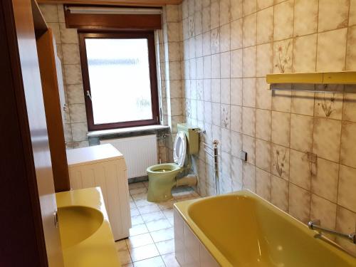 a bathroom with a yellow tub and a toilet at Monteurswohnungen Bruchsal Süd in Bruchsal