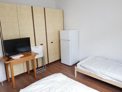 a room with a desk with a bed and a refrigerator at Monteurswohnungen Bruchsal Süd in Bruchsal