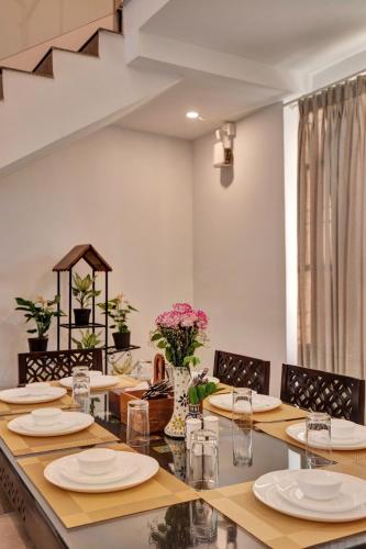 a dining room with a table with plates and flowers at ELIVAAS Horizon Luxe 5BHK Villa with Pvt Pool, Udaipur in Udaipur