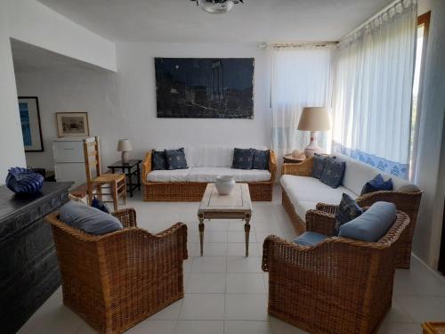 a living room with wicker chairs and a couch at Villa Porto Giunco in Notteri