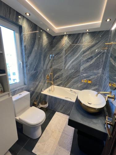 a bathroom with a toilet and a sink and a tub at LIVAS Athens Voula garden bungalow in Athens