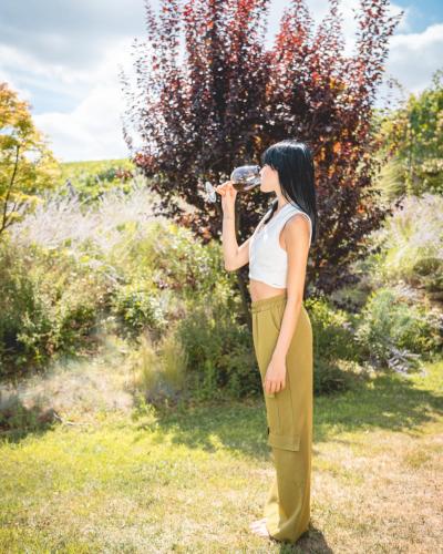 a woman standing in a field drinking from a bottle at Arborina Relais in La Morra