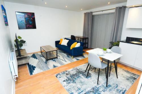 a living room with a blue couch and a table at Stylish Airport Apartment in Luton