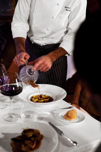 a chef is pouring sauce into a plate of food at Villa La Massa in Bagno a Ripoli