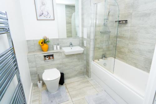 a bathroom with a toilet and a tub and a sink at Stylish Airport Apartment in Luton