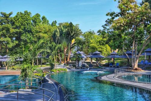 una piscina en un complejo con sillas y sombrillas en Royal Cliff Grand Hotel Pattaya, en Pattaya South