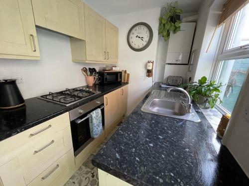 a kitchen with a sink and a clock on the wall at No 28 Sleeps 4 in the heart of Cowes in Cowes