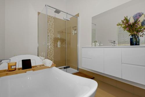 a white bathroom with a shower and a white bed at Sea Glass Cottages Burnie Tasmania in Burnie
