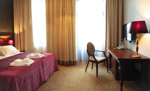 a hotel room with a bed and a desk and a chair at Hotel Akvilon in Suwałki