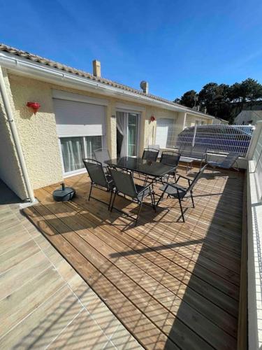 un patio avec une table et des chaises sur une terrasse dans l'établissement Maison 6 personnes Soulac Climatisée Fibre, à Soulac-sur-Mer
