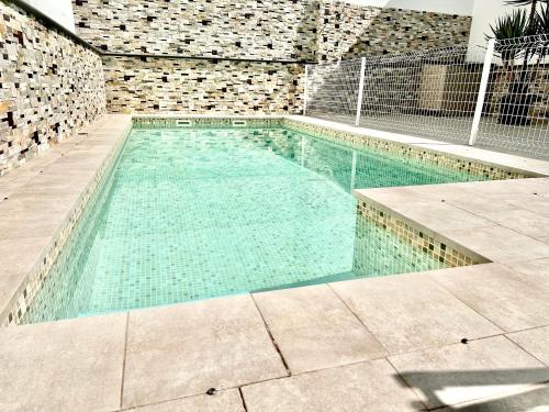 a swimming pool with turquoise water and a brick wall at CASA RURAL AREV in Herrera del Duque