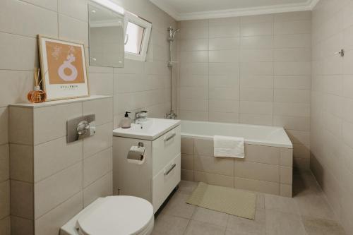 La salle de bains est pourvue de toilettes, d'un lavabo et d'une baignoire. dans l'établissement Holiday Agoston Apartments, à Timişoara