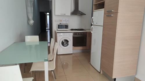 a kitchen with a table and a refrigerator and a washing machine at Super Located Ground Floor Apartment in St. Julianʼs