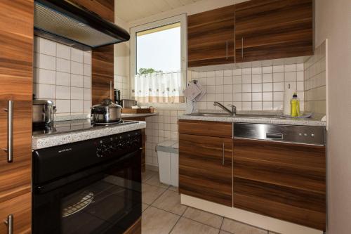 a kitchen with wooden cabinets and a black dishwasher at Ferienhaus Saturn im Sternenpark in Lochow