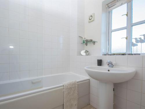 a white bathroom with a sink and a bath tub at 3 Bed in Studland DC072 in Studland