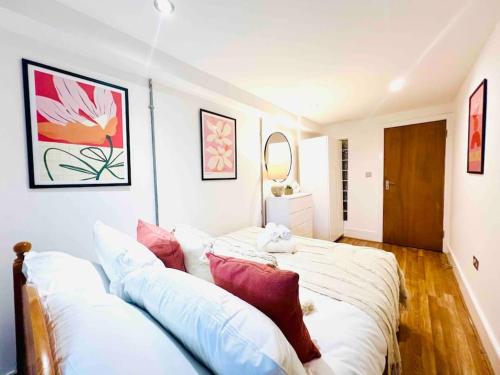 a bedroom with a large white bed with red pillows at Highgate Garden Apartment- 2 Bed in London