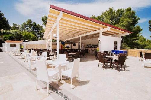 un restaurante con mesas y sillas blancas y un pabellón en Villaggio Elisena, en Vieste