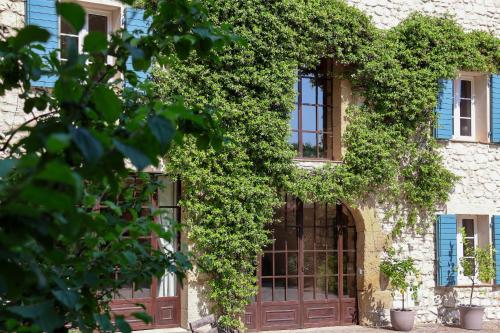 un edificio cubierto de hiedra con una puerta y ventanas en Domaine du Moulin de Villefranche, en Pernes-les-Fontaines