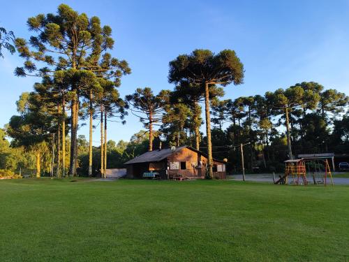 une cabane dans un champ avec des arbres et une aire de jeux dans l'établissement Cabanas Loft Paraíso, à Gramado