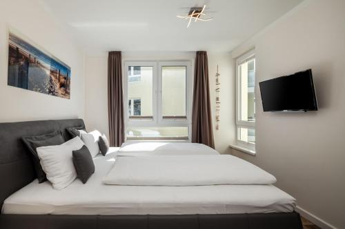 ein Schlafzimmer mit einem Bett und einem TV an der Wand in der Unterkunft mit Meerblick und Balkon, gratis Nutzung vom AHOI Erlebnisbad und Sauna in Sellin - Meeresblick FeWo 70 in Göhren