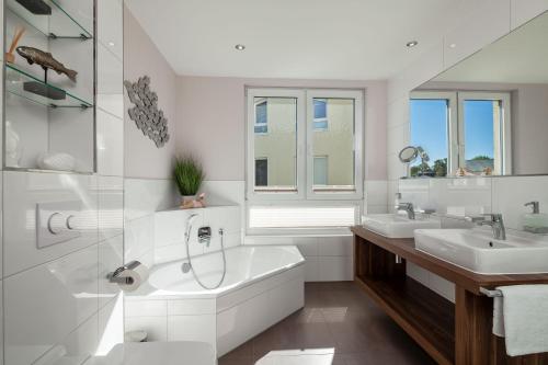 ein weißes Badezimmer mit zwei Waschbecken und einer Badewanne in der Unterkunft mit Meerblick und Balkon, gratis Nutzung vom AHOI Erlebnisbad und Sauna in Sellin - Meeresblick FeWo 70 in Göhren