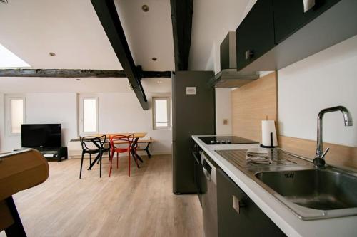une cuisine avec un évier et une table avec des chaises dans l'établissement T2 moderne et lumineux au cœur du centre historique, à Aix-en-Provence