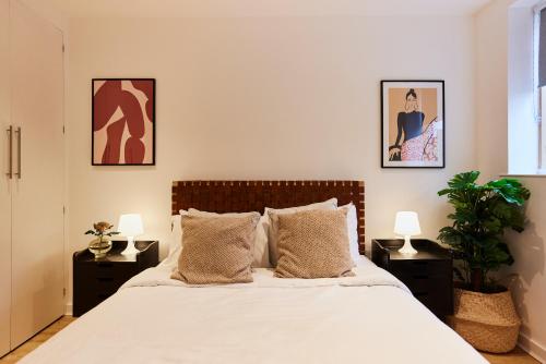 1 dormitorio con 1 cama con 2 mesitas de noche y 2 lámparas en The Putney Escape - Trendy 2BDR Flat with Terrace + Parking en Londres