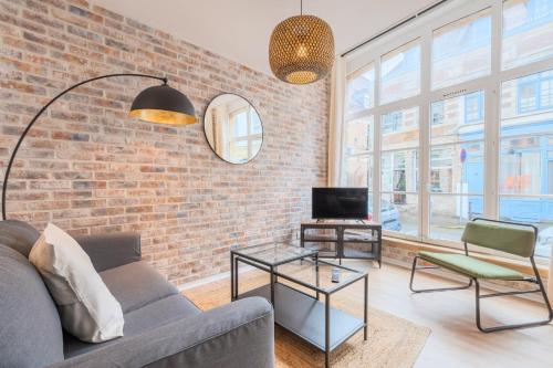 een woonkamer met een bank en een bakstenen muur bij Unique apartment in the Old Lille ! in Lille