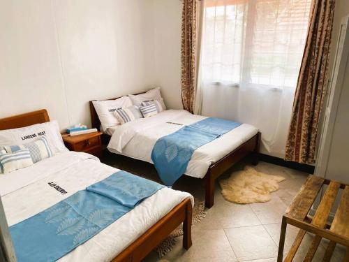 twee bedden in een kleine kamer met een raam bij 3 Bedroom Laneens Nest in Nakuru