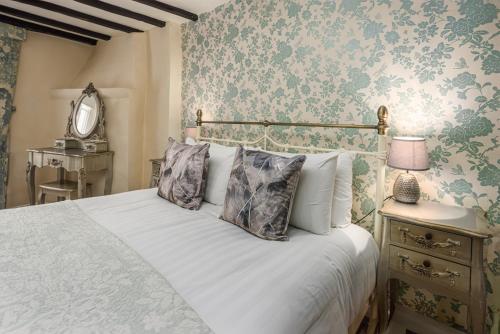a bedroom with a white bed with floral wallpaper at The Pied Bull in Chester