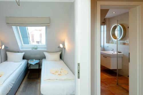 Cette petite chambre comprend 2 lits et un miroir. dans l'établissement Ferienhaus Ekke Nekkepenn1, à Westerland