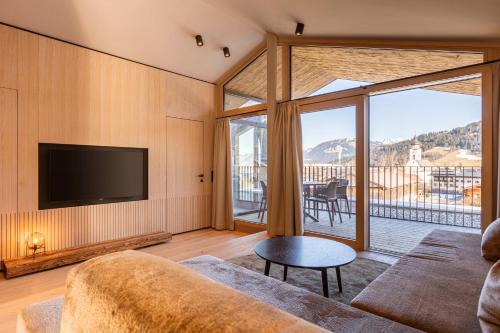 a living room with a couch and a flat screen tv at Kitzbühel Suites by ALPS RESORTS in Oberndorf in Tirol
