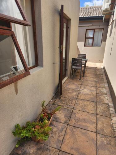 a patio with a table and chairs next to a building at Dilisca Guesthouse in Durbanville