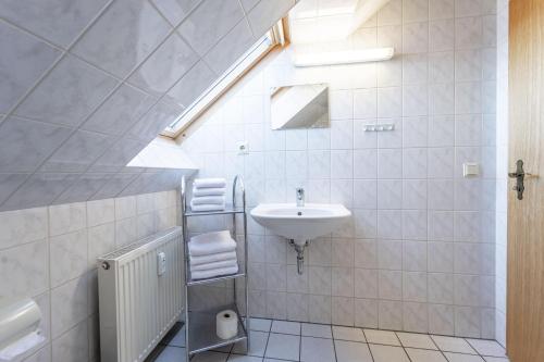 La salle de bains blanche est pourvue d'un lavabo et d'une lucarne. dans l'établissement Wanderlust Wernigerode - Dein Tor zum Harzer Abenteuer, à Wernigerode