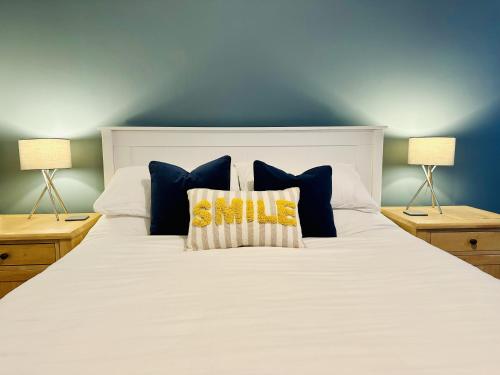 uma grande cama branca com almofadas e 2 candeeiros em Coastal Cottage with hot tub, sleeps 10 em Bacton