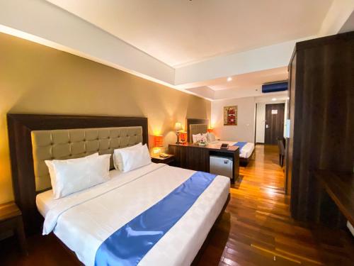 a bedroom with a large bed and a desk at Luxury Malioboro Hotel in Yogyakarta