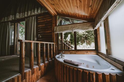 Tsitsikamma Lodge & Spa في ستورمزريفير: حوض استحمام في غرفة مع نافذة