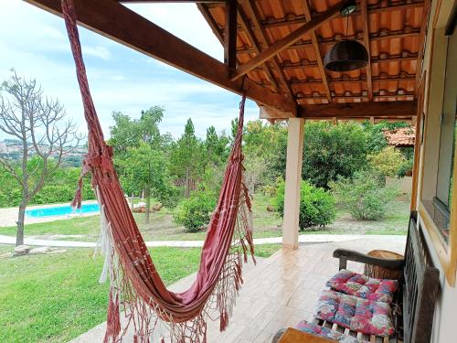 a hammock on a porch with a view of a yard at Toca dos Coelhos Chalés in Carrancas