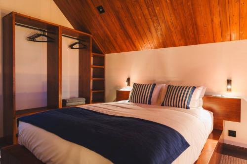 sypialnia z dużym łóżkiem i drewnianym sufitem w obiekcie Cabanas do Pico 2a w mieście São Roque do Pico