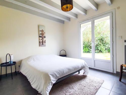 een witte slaapkamer met een bed en een raam bij DUNES - Villa Patio Avec Jardin - proche Plage de la Gravière in Soorts-Hossegor