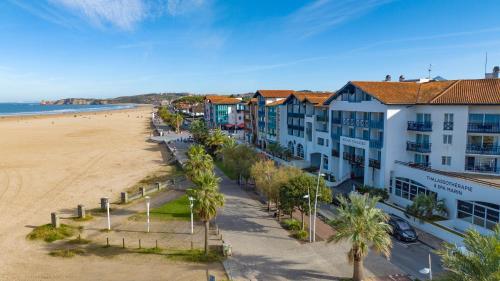 eine Luftansicht auf einen Strand mit Gebäuden und Palmen in der Unterkunft Hotel & Spa 4* Serge Blanco in Hendaye