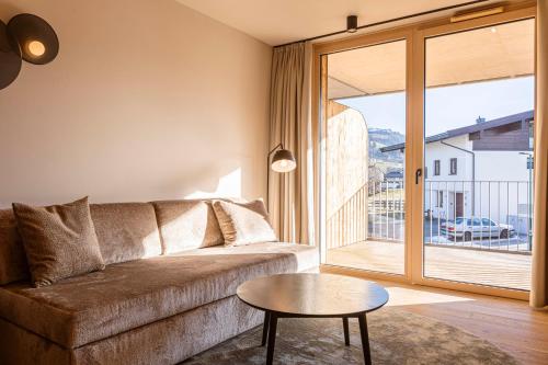 a living room with a couch and a table at Kitzbühel Suites by ALPS RESORTS in Oberndorf in Tirol