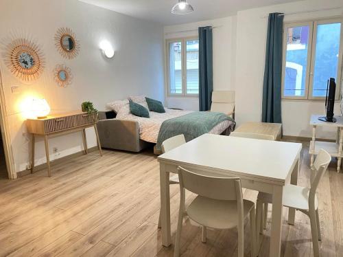uma sala de estar com uma cama, uma mesa e cadeiras em Chic'appart em Cavaillon