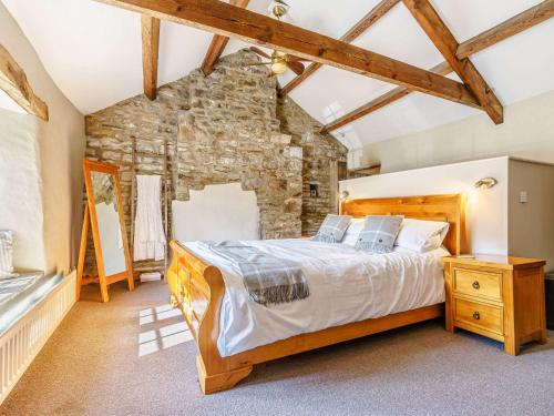 1 dormitorio con cama y pared de piedra en 5 bed in Reeth 81457 en Gunnerside