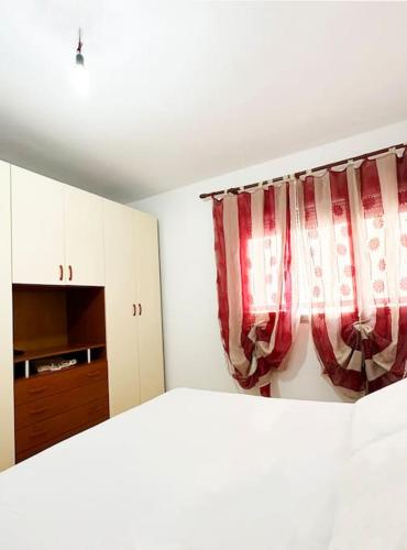 ein Schlafzimmer mit einem roten Vorhang und eine Küche in der Unterkunft LD Apartment in Vlorë